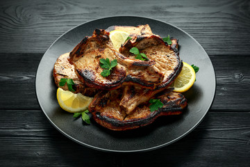 Homemade Grilled Pork loin chops in lemon sauce with herbs on rustic wooden table