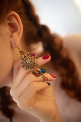 Colorful bright earring on a beautiful red-haired girl.