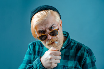 Man smoking. Close up portrait of handsome guy in shirt isolated on blue background.