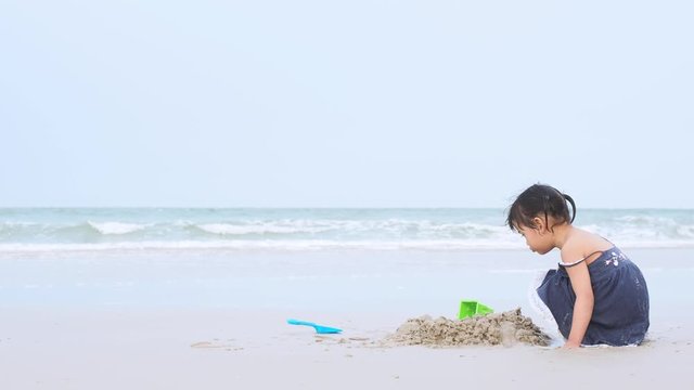 Asian little girl 4 years old are playing sand and explore the life on the beach. Huahin Beach, Prachuap Khiri Khan,Thailand.