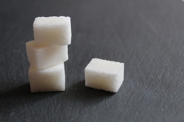 three or four lumps of sugar lie in a column on the table against a dark background