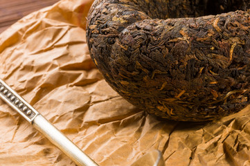Chinese pressed PU-erh tea on wrapping paper and tea accessories, close-up, macro