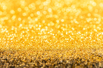 Gold glitter texture. Sparkling gold bright bokeh from blurred diamond dust on black background. Abstract golden bokeh background. Selective focused