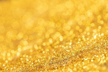 Gold glitter texture. Sparkling gold bright bokeh from blurred diamond dust on black background. Abstract golden bokeh background. Selective focused
