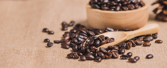 Close up roasted coffee beans on sackcloth with wooden bowl and tea spoon