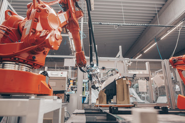 Close up of automatic robot arms in automotive industry, factory production of headlamps for a...