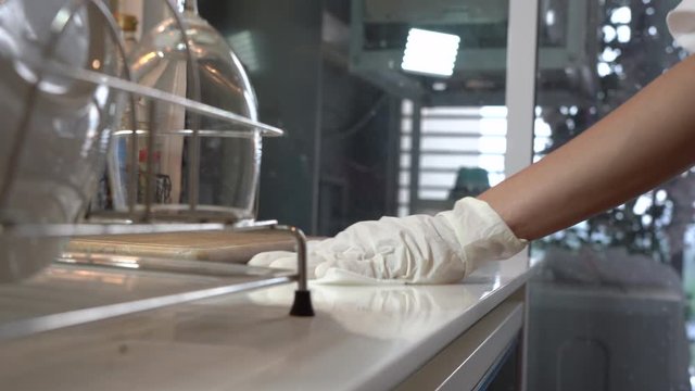 Housewife hands with white gloves  disinfects sanitize and clean kitchen, spray wipe counter surfaces area, at home, stop virus from spreading, corona virus covid19, killing germs, health care concept