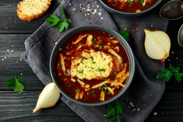 French onion soup with cheese toast on rustic background