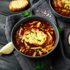 French onion soup with cheese toast on rustic background