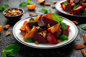 Vegan Plum, beet salad with pecan nuts, mint and herbs on rustic black table