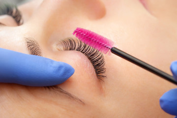 Eyelash extension procedure close up. Beautiful woman with long eyelashes in a beauty salon. Makeup...