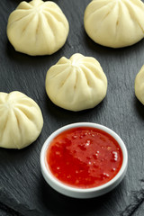 Steamed Buns with duck stuffing, chili sauce on rustic stone board. Asian food