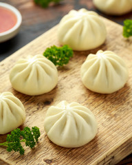 Steamed Buns with duck stuffing, chili sauce on wooden board. Asian food.