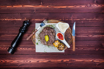 Delicious grilled steak with sauces and fried corn. There is a pepper grinder and cutlery. Top view