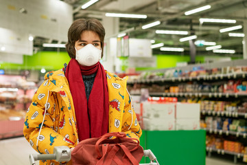 young woman in a protective mask chooses alcohol in a supermarket, stocks are quarantined