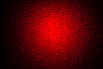 Drops of water on glass in red neon light. Rain on the glass against the background of colored...