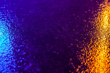 Abstract photo reflection of light on a wet surface. Blue-yellow neon light on a textured wet...