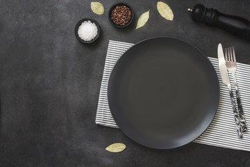 Empty black slate plate on dark stone table and napkin.