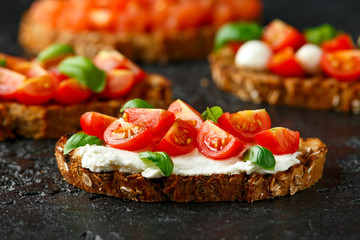 Bruschetta with ricotta cheese, basil, cherry tomato on rustic table