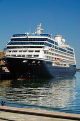 Luxury classic cruiseship or cruise ship liner in port with pier and reflection on water on summer...