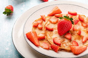 Pancakes with fresh strawberry on a blue wooden background