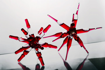 Glass ampoules with a red medicine vitamine b12 glued together in a spider shape on a glass...