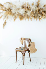 Straw bag on white background template. Wicker bag and wooden vintage chair. Summer interior concept mock up. Autumn elegant dry grass and pampas composition.