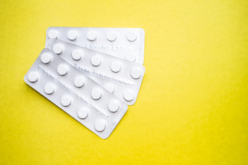 Medical pills in plastic packaging on a yellow background