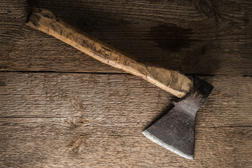 Old axe with a wooden haft on a background of rough wood texture.