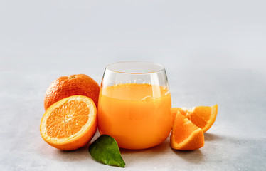 Fototapeta na wymiar A glass of freshly squeezed orange juice with oranges