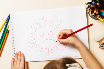 A small child in home quarantine draws a coronavirus, top view