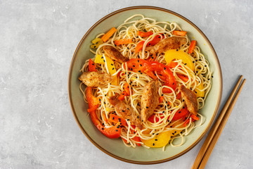 Top view of vegan stir fry in a bowl on grey background