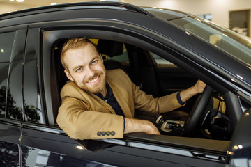 happy caucasian guy made purchase in dealership, he is happy to get a new car. business class car, vehicle, transport, automobile, car concept