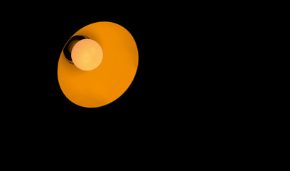 orange desk lamp on black background