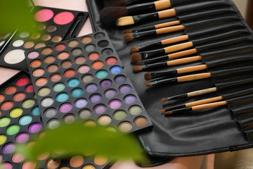 A palette of shadows and brushes on the table next to the flowers