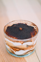 Italian dessert tiramisu  in a transparent glass on a wooden table.