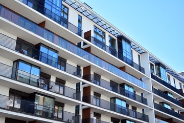 Obraz premium Contemporary residential building exterior in the daylight. Modern apartment buildings on a sunny day with a blue sky. Facade of a modern apartment building