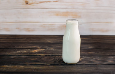 Fresh milk on a black wooden background in a glass bottle.
