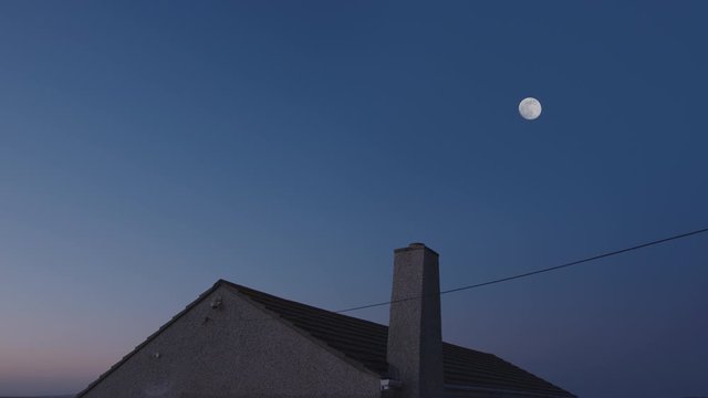 Full moon over house on a clear night.
