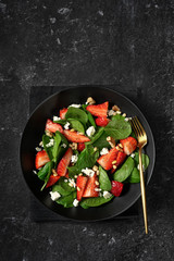 Strawberry and spinach spring salad in a black plate