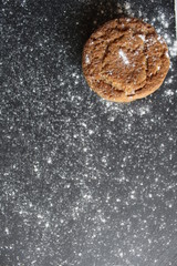 oatmeal cookies with home made cracks lie in a corner on a gray stone a black background with powdered sugar and space for text