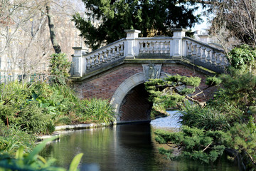 Fototapeta na wymiar Beautiful old stone bridge with railing over clean river in preserve