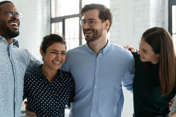 Overjoyed young diverse colleagues have fun laugh in office, smiling multiracial businesspeople coworkers engaged in funny creative teambuilding activity at workplace, unity, teamwork concept