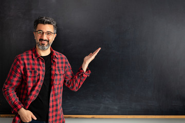 Adult man teacher showing empty blackboard.