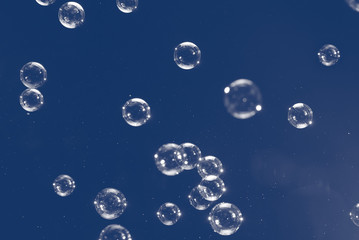 Flying soap bubbles isolated on blue background. Abstract background.