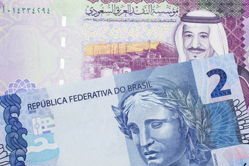 A five Saudi riyal bank note with a blue two Brazilian reais bill.  Shot in macro.