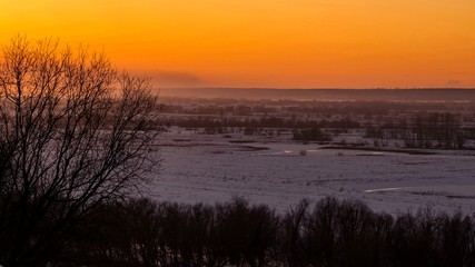 Beautiful sunset with clouds over a snowy plain and river bend