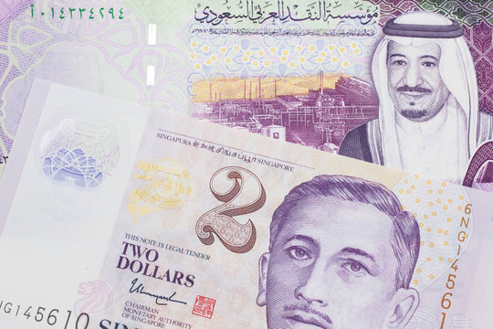A close up image of a five Saudi riyal bank note from the Saudi Arabia in macro with a two dollar bill from Singapore
