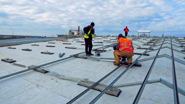 Workers install metal base for solar panels. Construction of new solar farm under the motion of clouds in the sky. Time lapse.