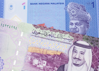 A blue, one ringgit Malaysian note close up in macro with a five riyal note from the Saudi Arabia
